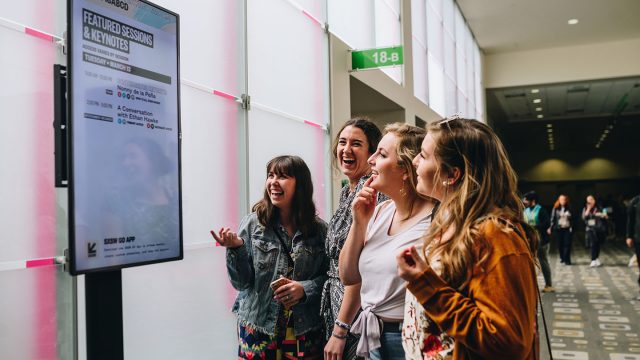 Girls looking at digital sign at SXSW 2018 - Photo by Judy Won